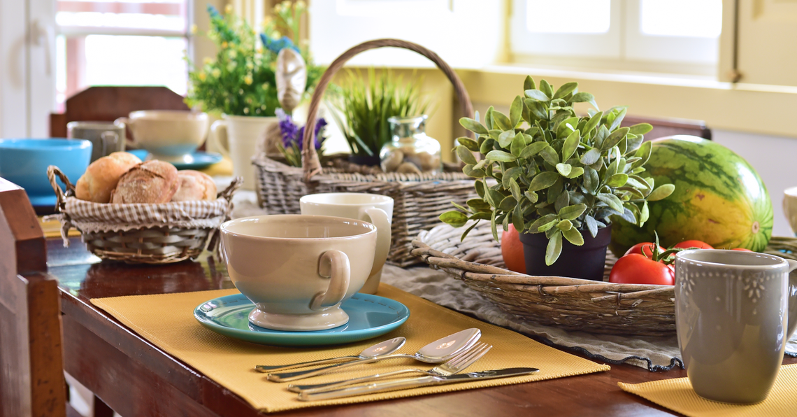 uma mesa com xícaras e pratos e uma cesta de legumes