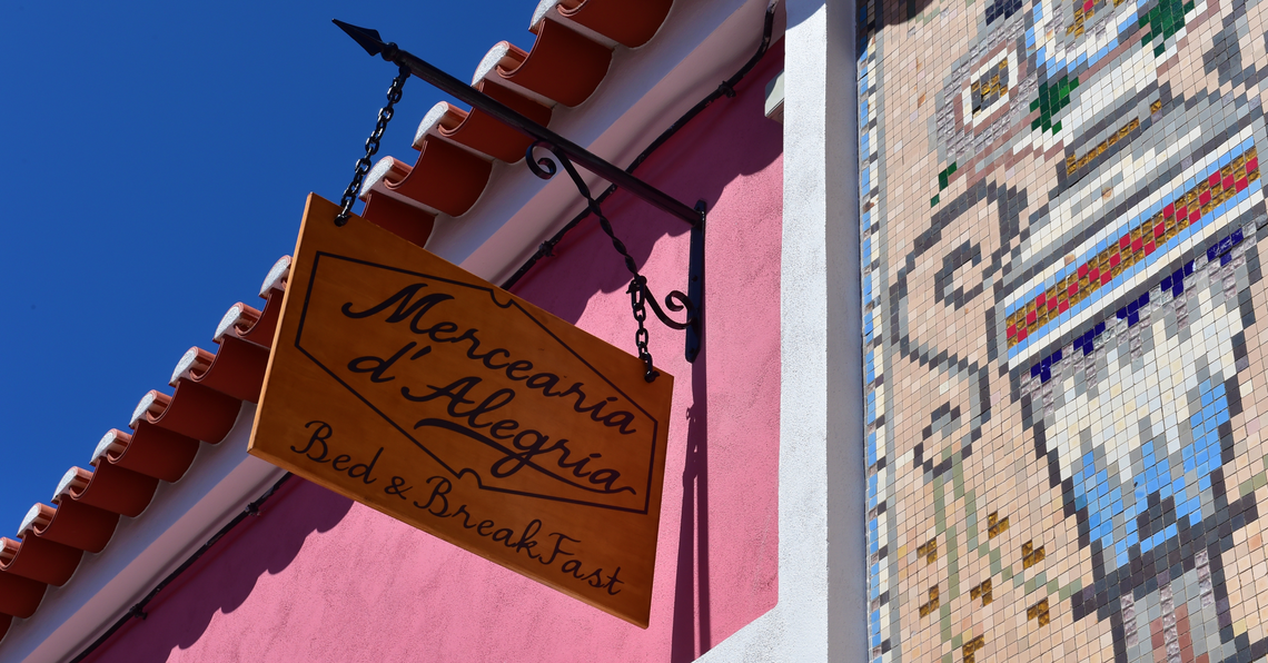 um sinal de madeira com a palavra mercearia d alegria sobre ele