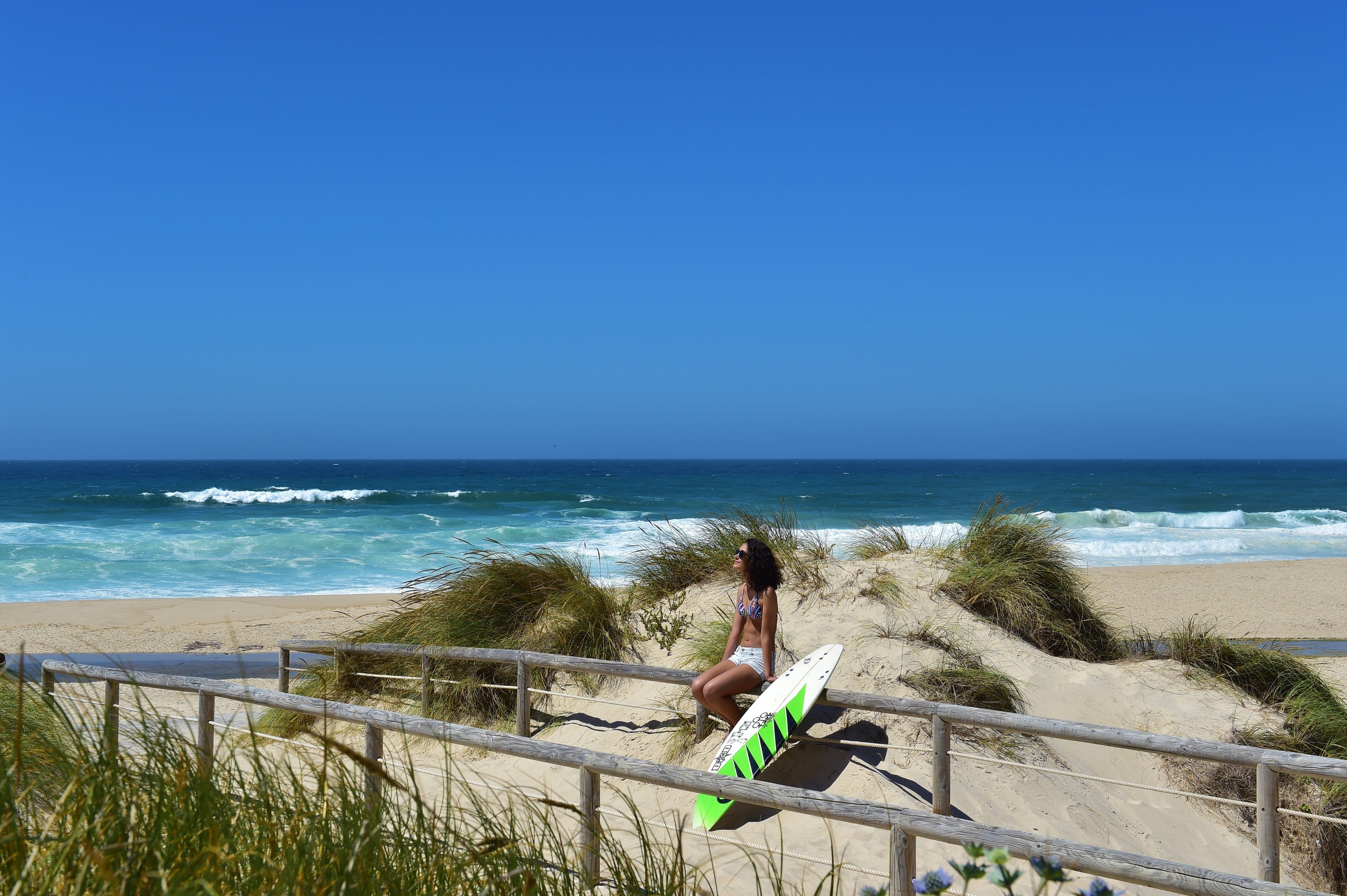 a wetsuit is hanging on a wooden fence next to a row of surfboards .
