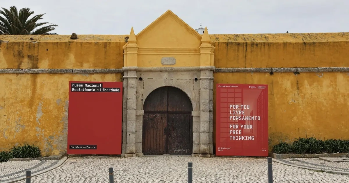a yellow building with a wooden door and a red sign on the side .
