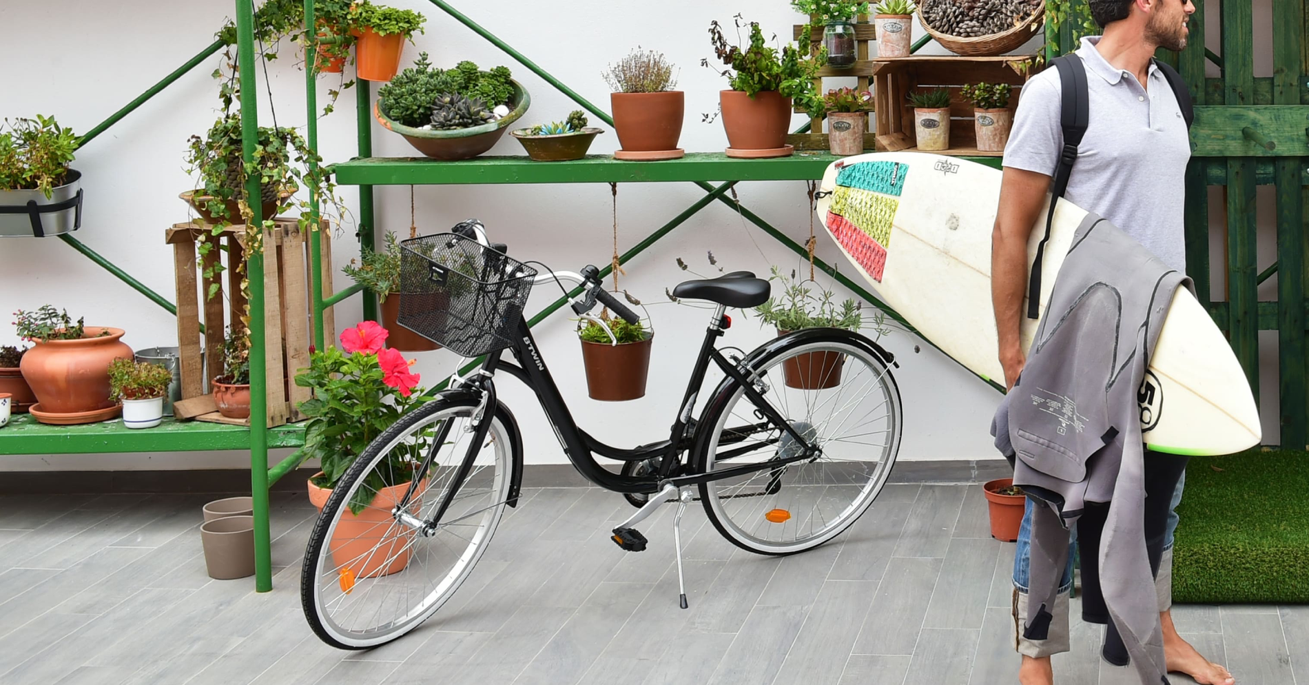 um homem carrega uma prancha de surf ao lado de uma bicicleta