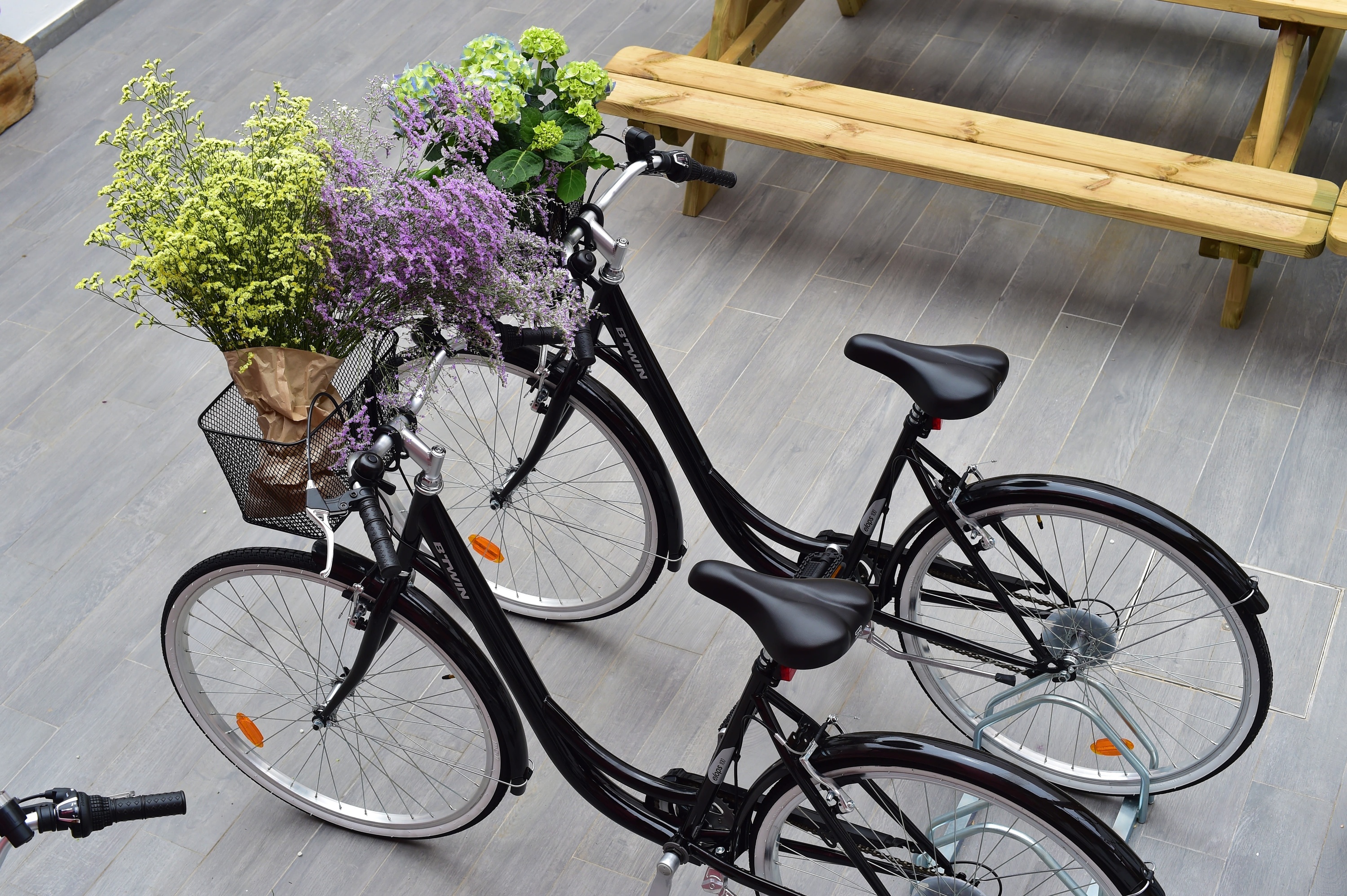 duas bicicletas com flores na cesta estão em um rack