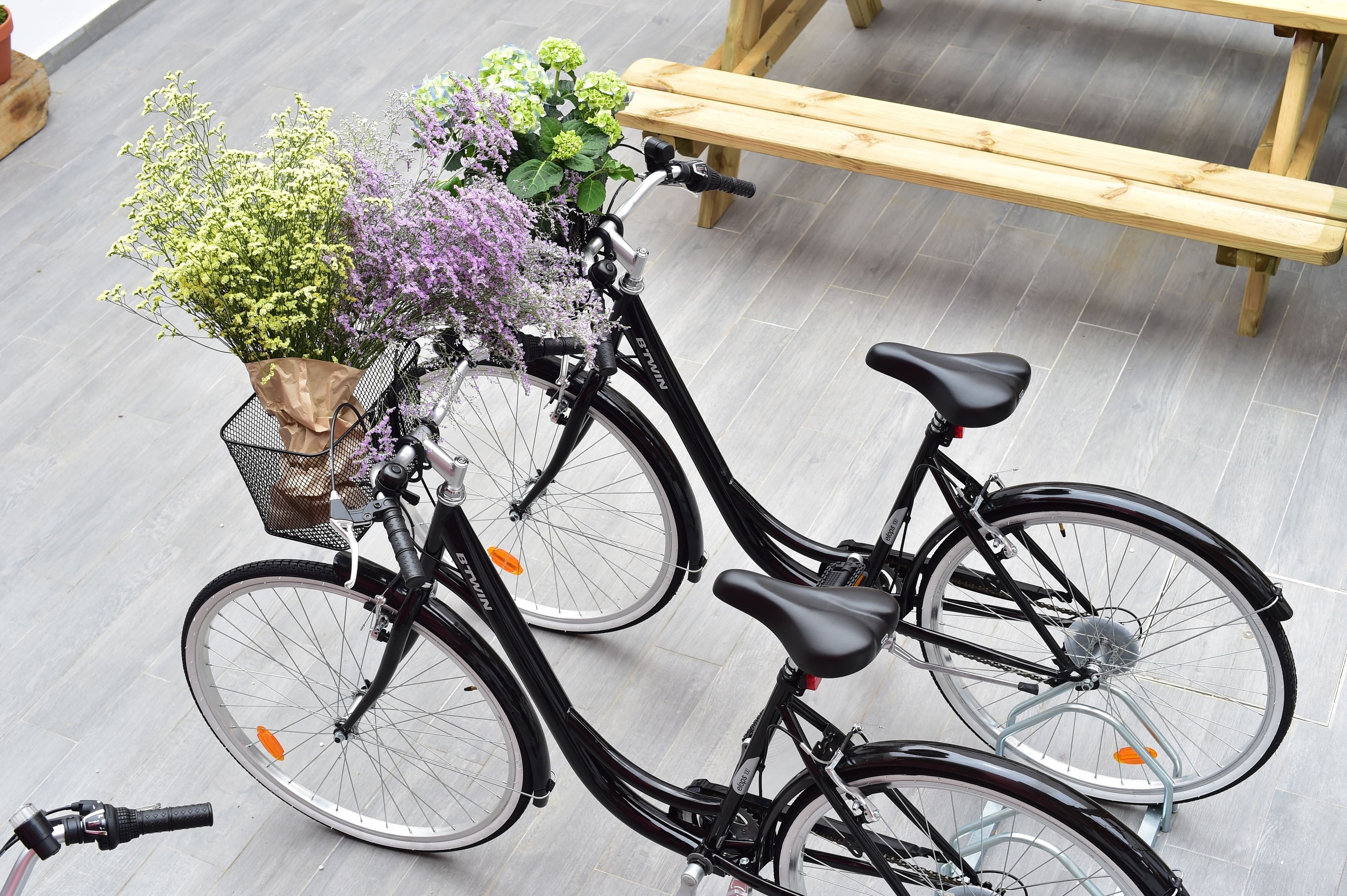 duas bicicletas com uma cesta cheia de flores