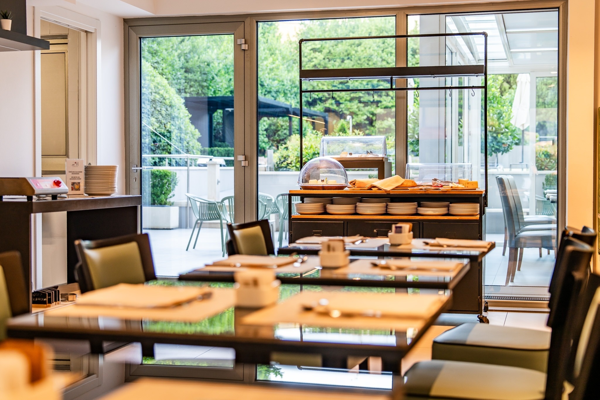 a person holding a glass of wine sits at a table with food