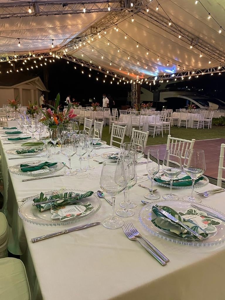 una mesa larga está decorada para una fiesta con platos y copas de vino