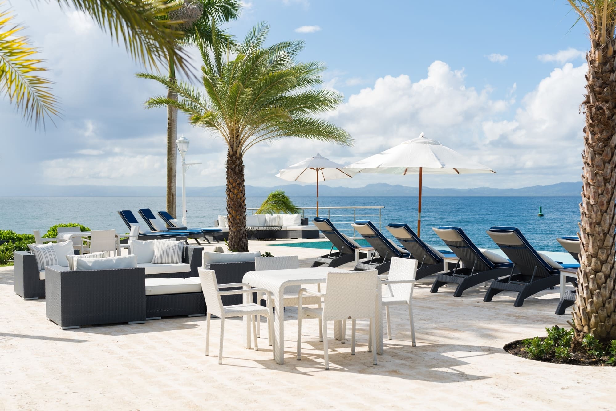 a patio with tables chairs and umbrellas overlooking the ocean