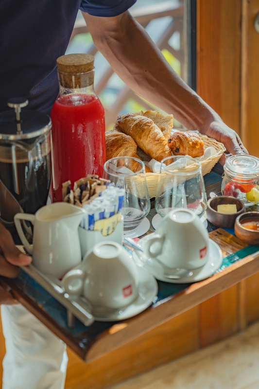 un hombre lleva una bandeja de comida con tazas de café illy