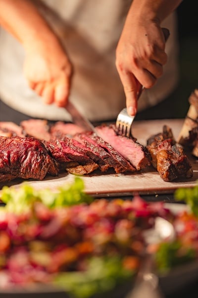 a person is cutting a large piece of meat on a cutting board