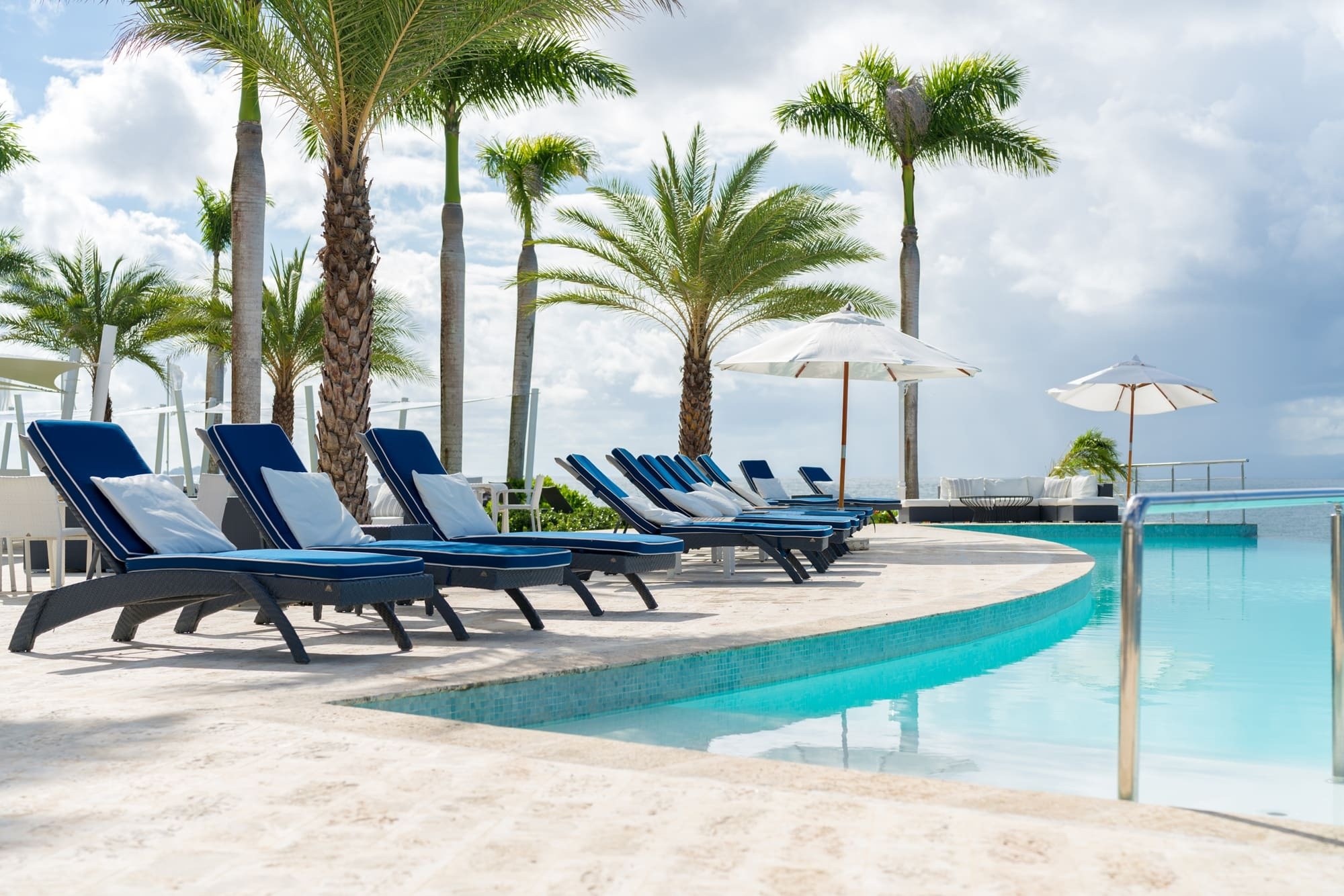 a swimming pool with blue chairs and white umbrellas