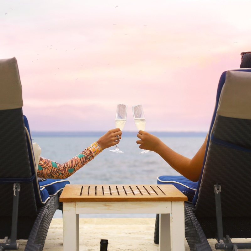 two people toasting with champagne glasses on the beach