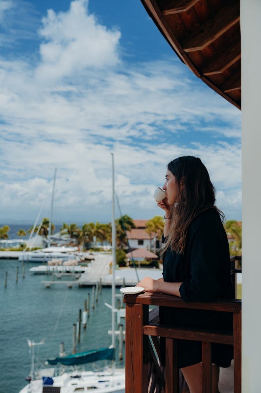 a woman sitting on a balcony drinking a cup of coffee