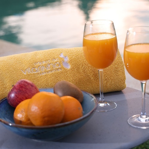 two glasses of orange juice next to a bowl of fruit and a yellow towel that says violine