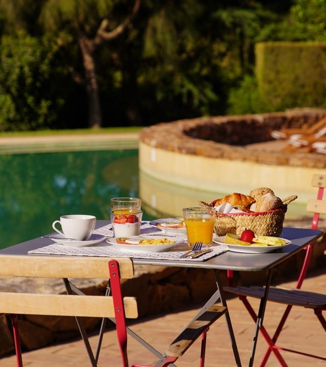 uma mesa com comida e suco de laranja ao lado de uma piscina