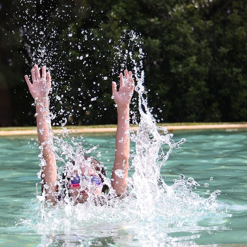 a child is splashing water in a swimming pool