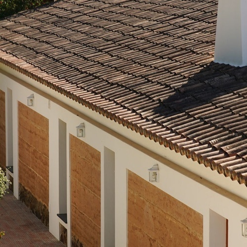 un edificio con un techo de tejas marrones y paredes blancas