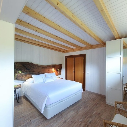 un dormitorio con una cama blanca y un techo de madera