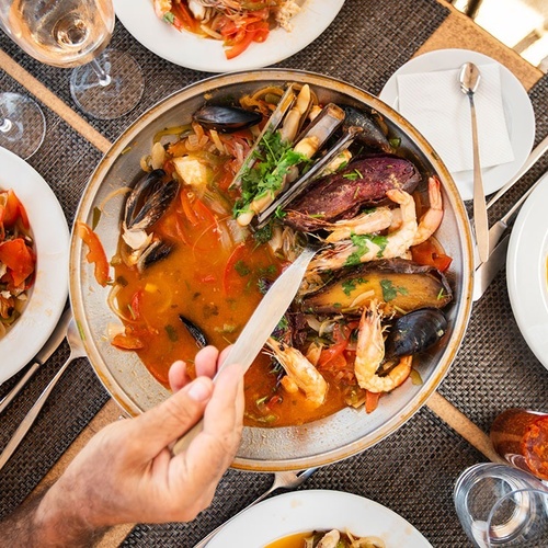 una persona sostiene un cuchillo frente a un plato de mariscos