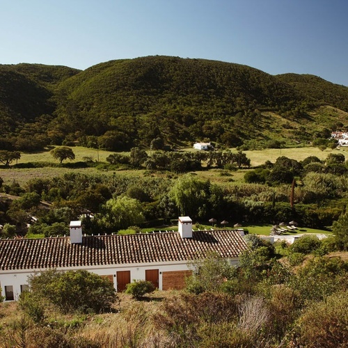 una casa blanca está rodeada de árboles y montañas