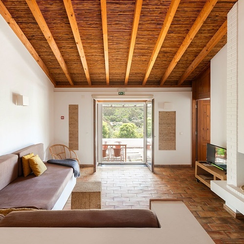 a living room with a wooden ceiling and a fire extinguisher on the wall