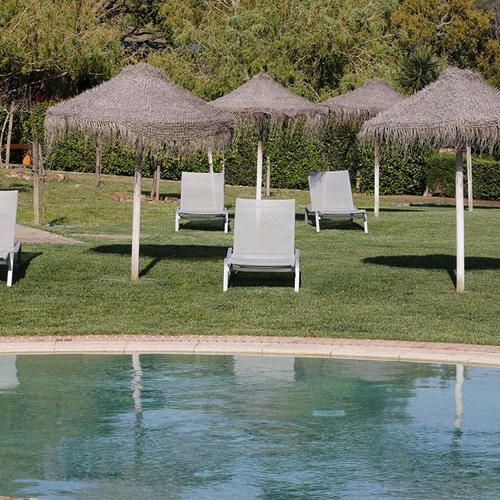 una piscina con sillas y sombrillas alrededor de ella