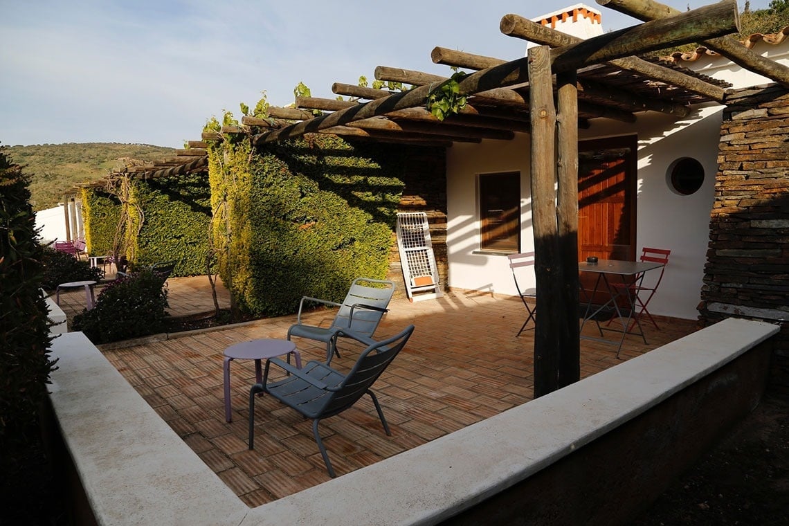 um pátio com cadeiras e mesas sob uma pérgola de madeira