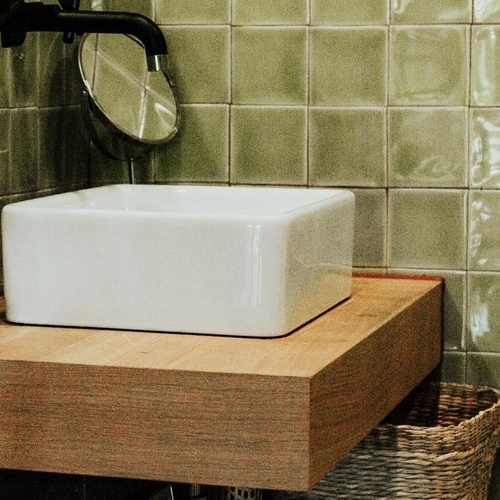 un baño con azulejos verdes y un lavabo blanco
