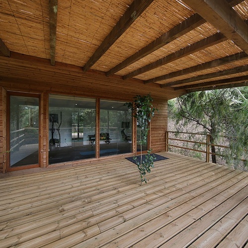 a wooden deck with a bamboo roof and sliding glass doors