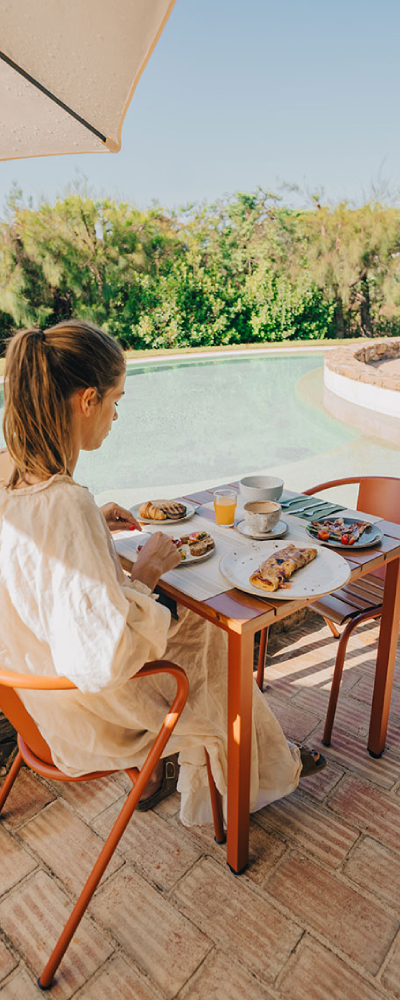 uma mesa com comida e bebidas em frente a uma piscina