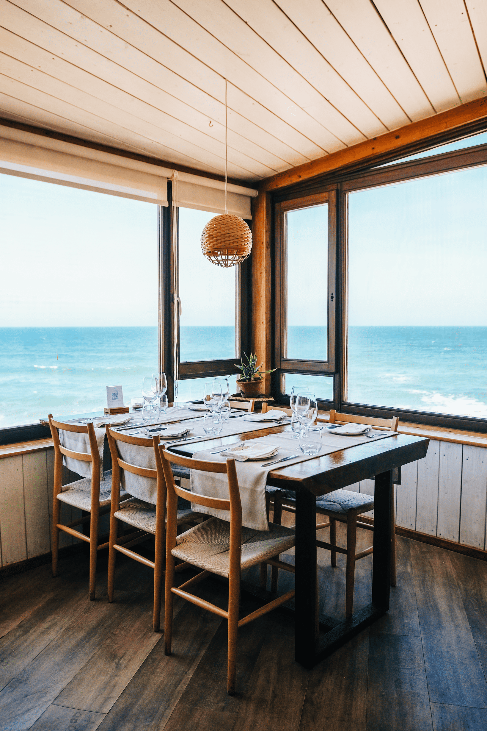 a table and chairs in a room with a view of the ocean