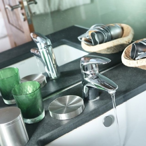 un baño con un lavabo y un espejo y una botella de keune