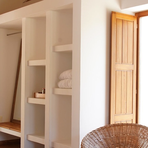 un armario con estantes y una silla de mimbre junto a una ventana