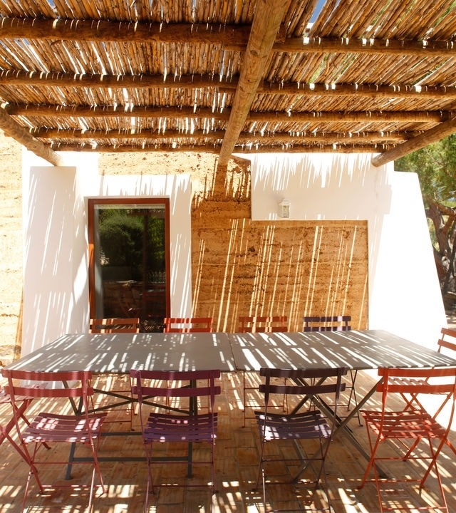 uma mesa e cadeiras coloridas sob um telhado de palha
