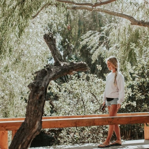 una mujer camina por un puente de madera en medio de un bosque