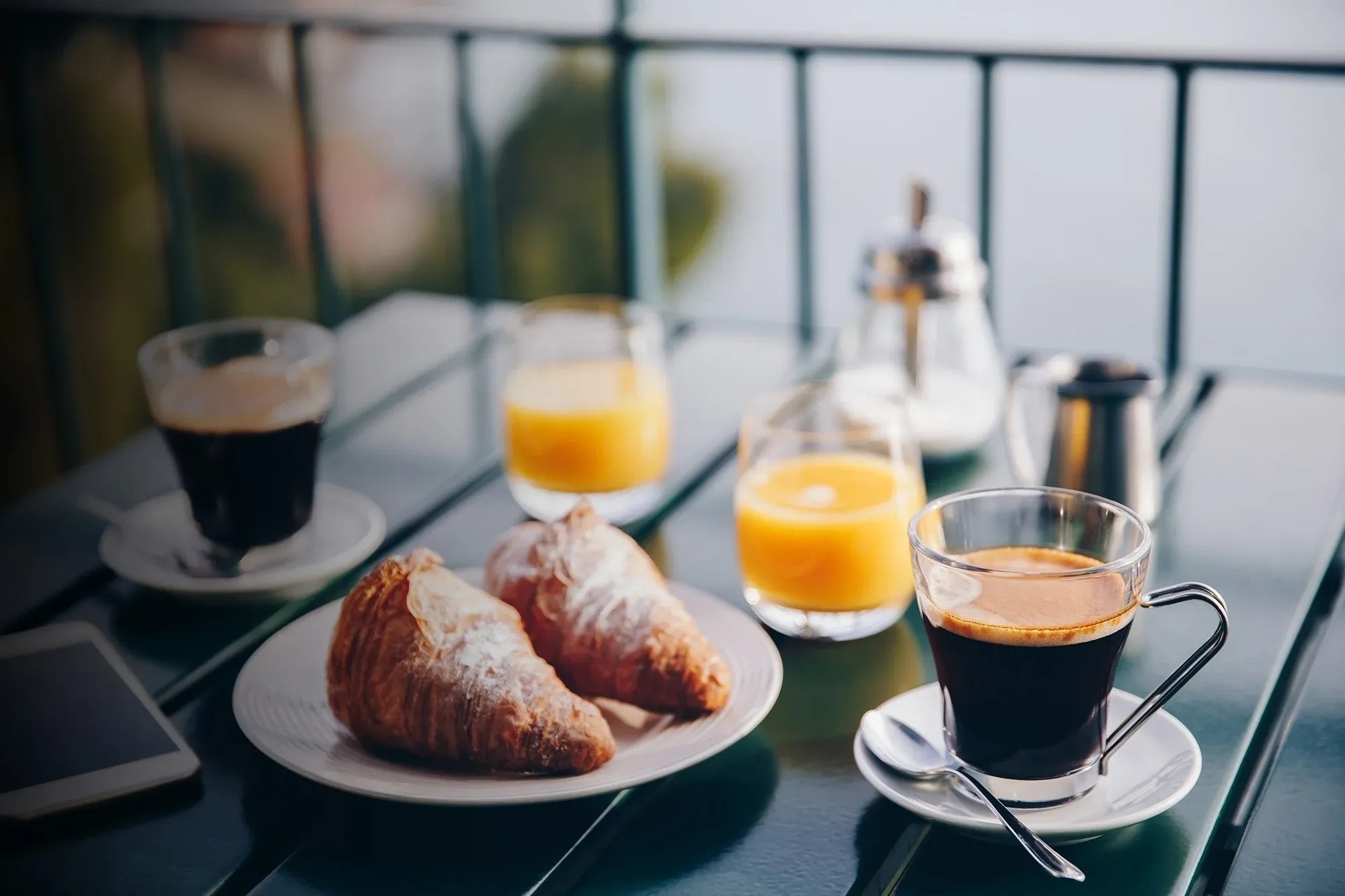 una mesa con croissants , café y zumo de naranja