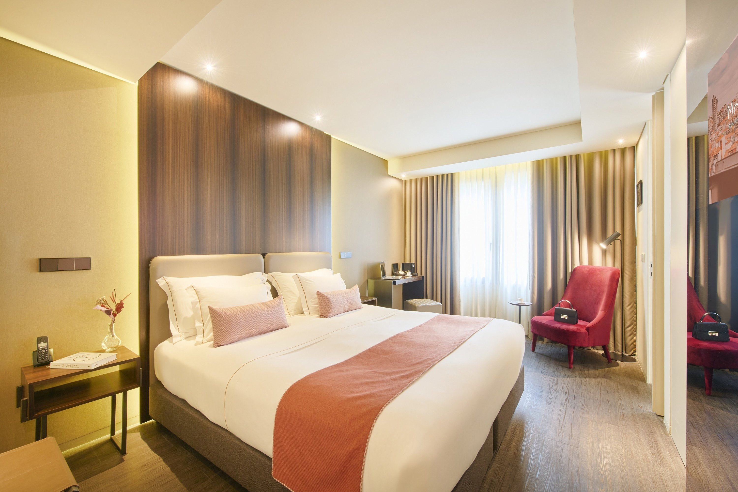 a hotel room with a large bed and a red chair