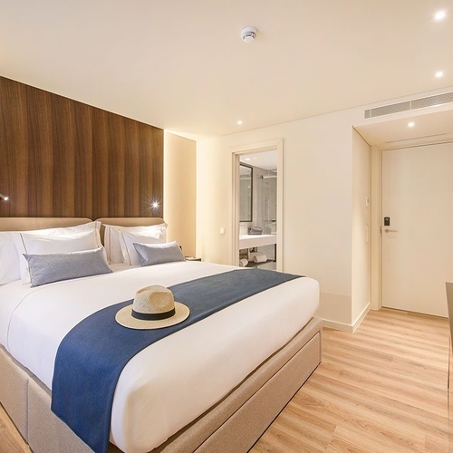 una habitación de hotel con una cama king size y un sombrero en la cama