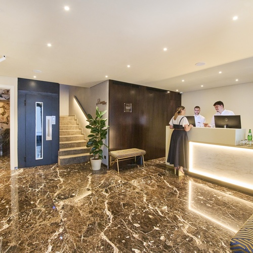 a woman stands at a reception desk in a hotel lobby