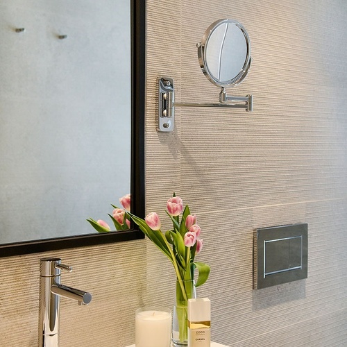 un baño con un espejo y un jarrón de flores