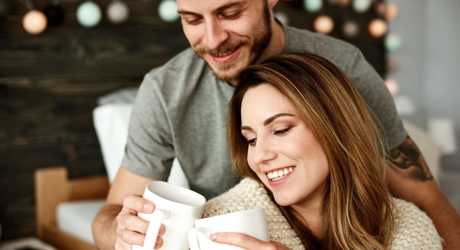 a man and a woman are holding cups of coffee and smiling