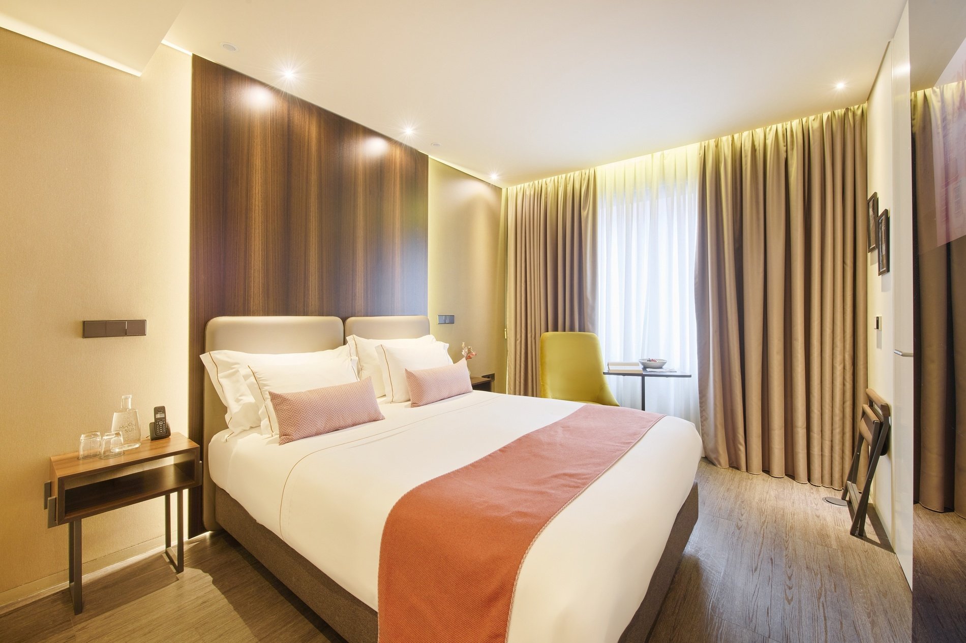 a hotel room with a large bed and a yellow chair