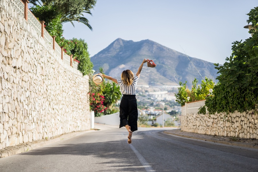 Woman celebrating with a hat and sandal, possibly at Moon & Sun: Corpo resort.