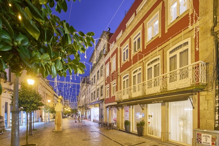 a frente de um prédio vermelho e branco com a cidade de lisboa ao fundo