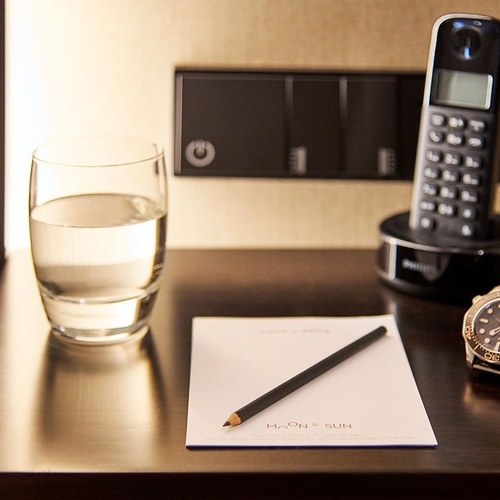 a glass of water sits on a table next to a notepad and a watch