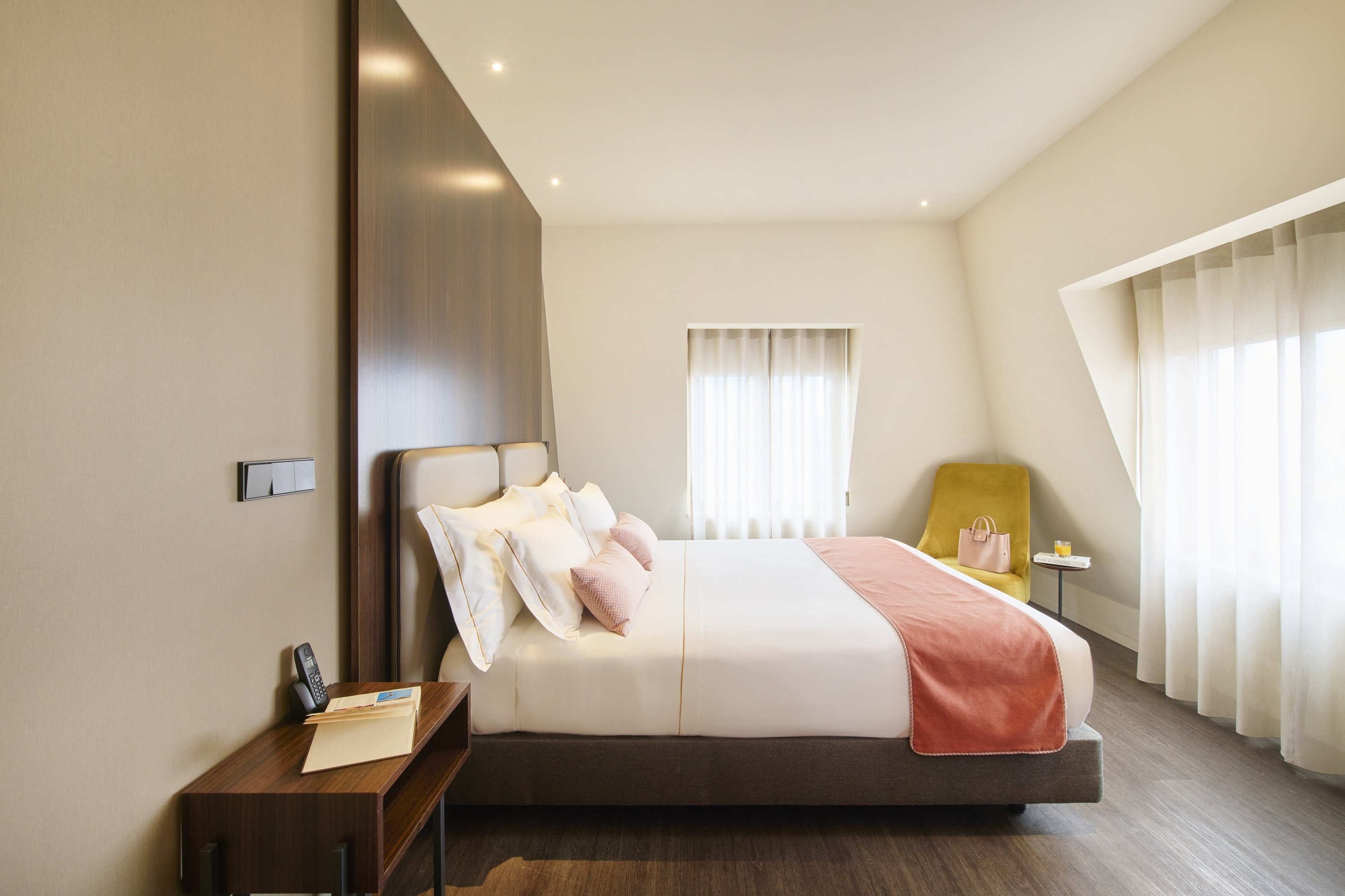 a hotel room with a large bed and a yellow chair