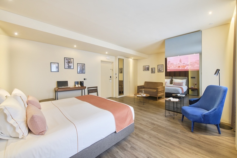 a hotel room with a large bed and a blue chair