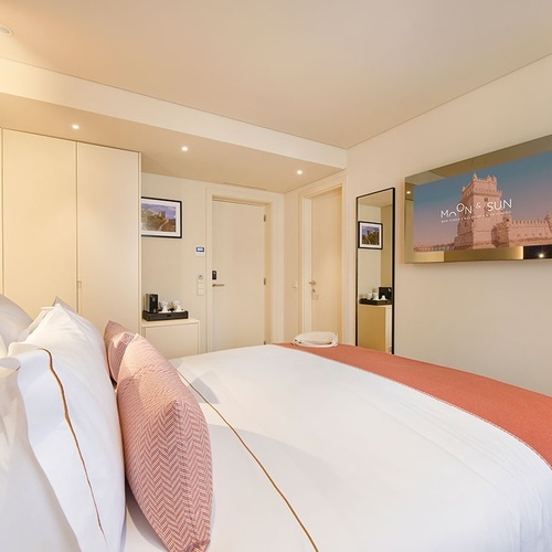 um quarto de hotel com uma cama e uma televisão que diz moon & sun