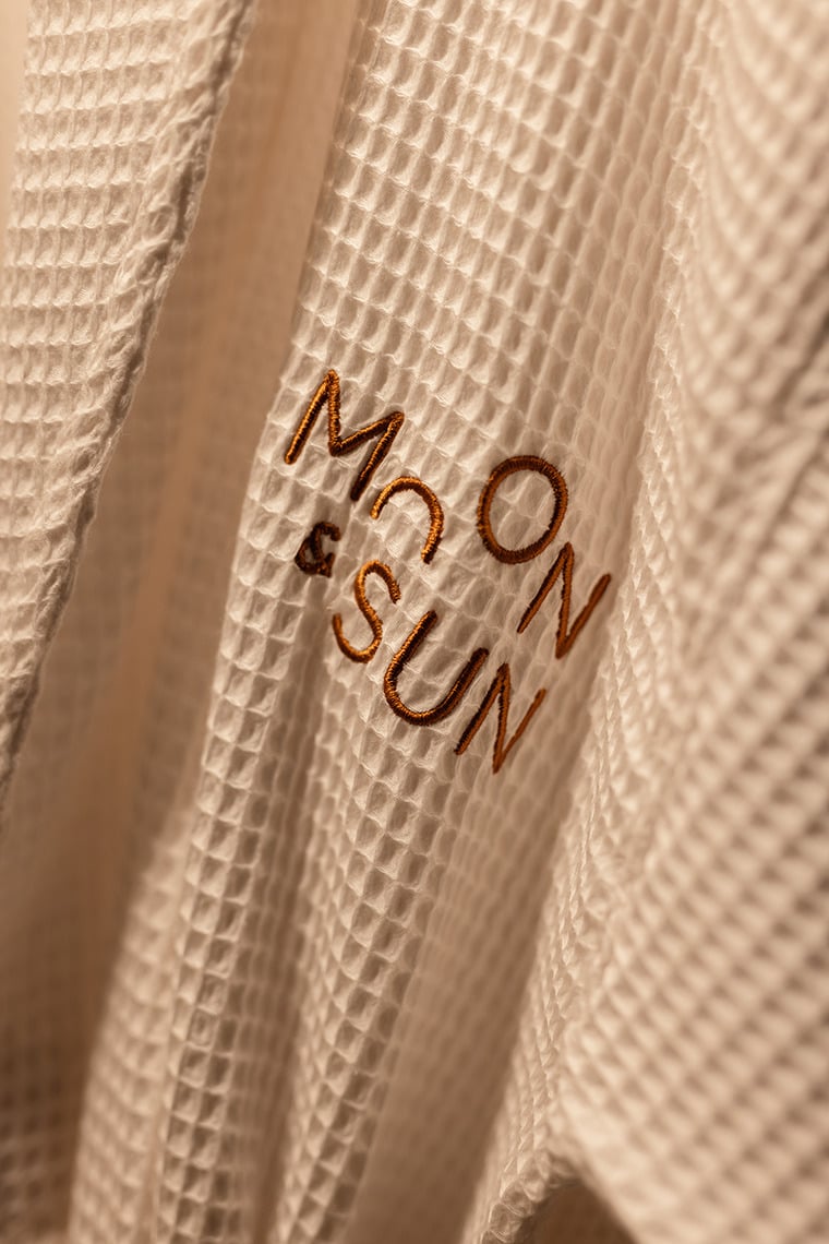Embroidered Moon & Sun: Corpo logo on a textured waffle weave robe.