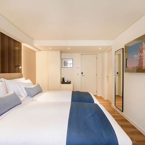 um quarto de hotel com duas camas e uma tela de tv