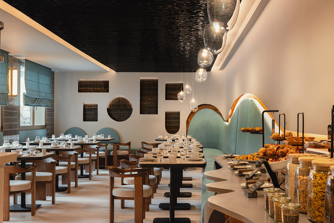 Elegant hotel breakfast buffet setup with pastries, cereals, and dining tables ready for guests. Moon & Sun: Corpo