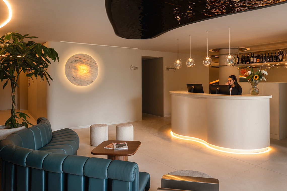 Modern hotel lobby with reception desk, stylish seating, and ambient lighting. Moon & Sun: Corpo.